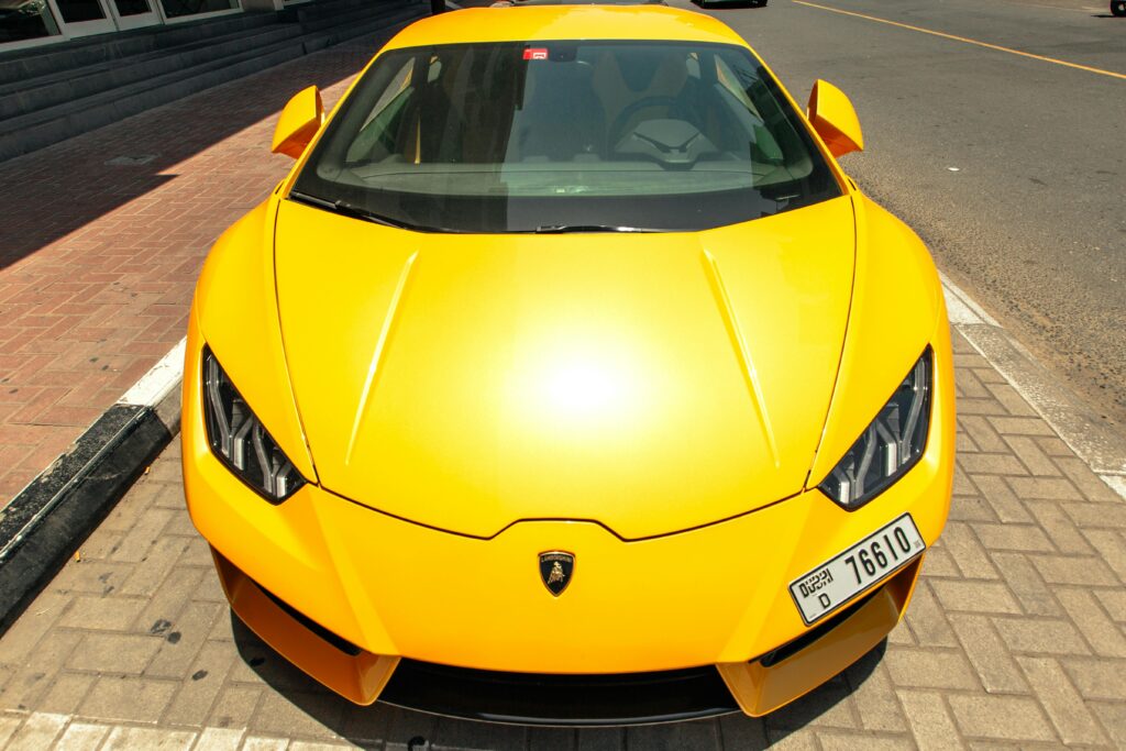 Front view of a parked yellow Lamborghini Aventador on a sunny Dubai street.