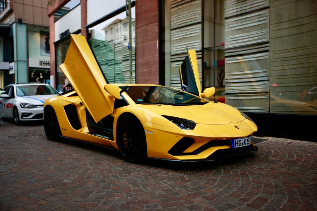 A striking yellow Lamborghini with open doors parked in a city street, showcasing luxury and style.